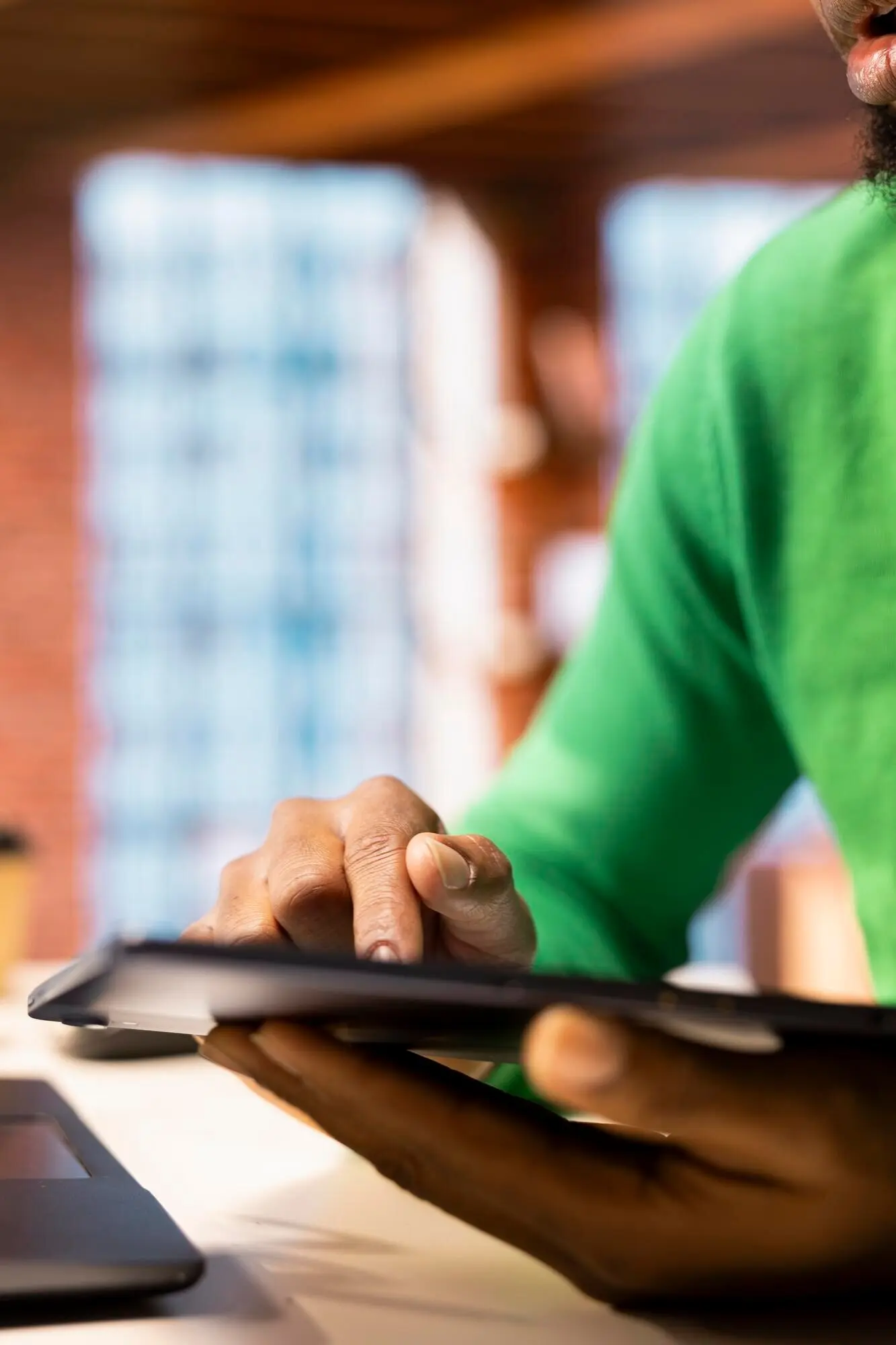 Мужчина в гостиной использует планшет, чтобы писать посты в социальных сетях.