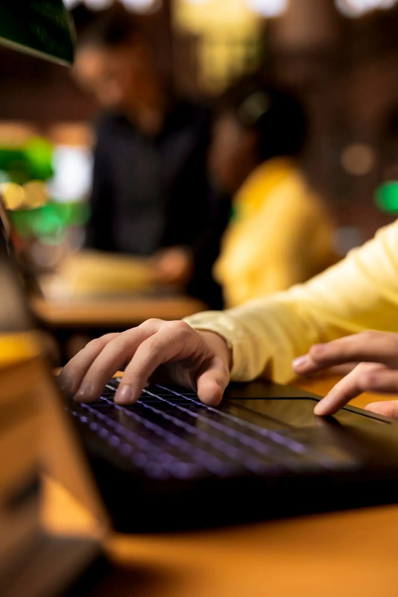 Ученица начальной школы пишет сочинение на своем ноутбуке, используя библиотечные книги.